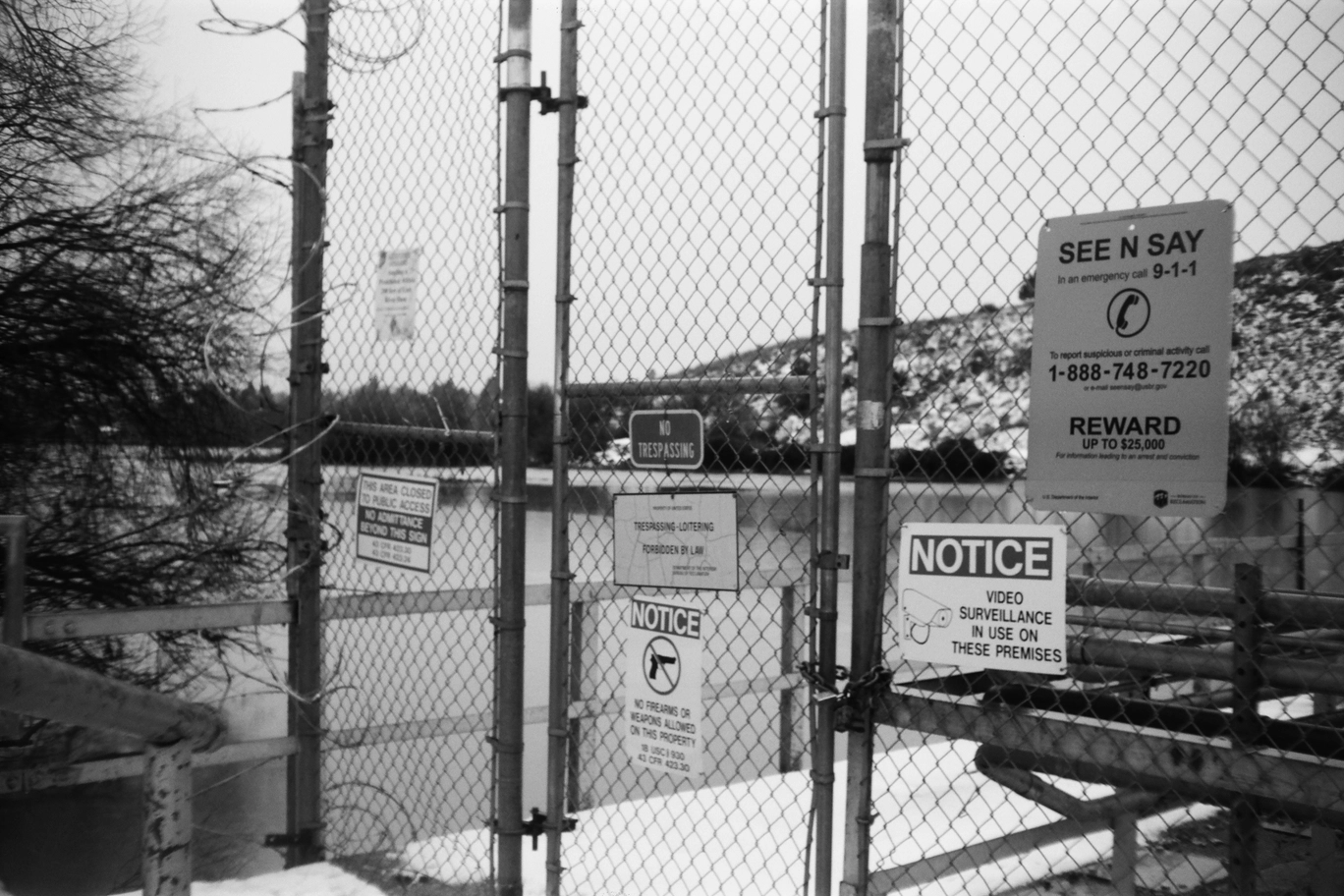A photo of a fence with many warning signs