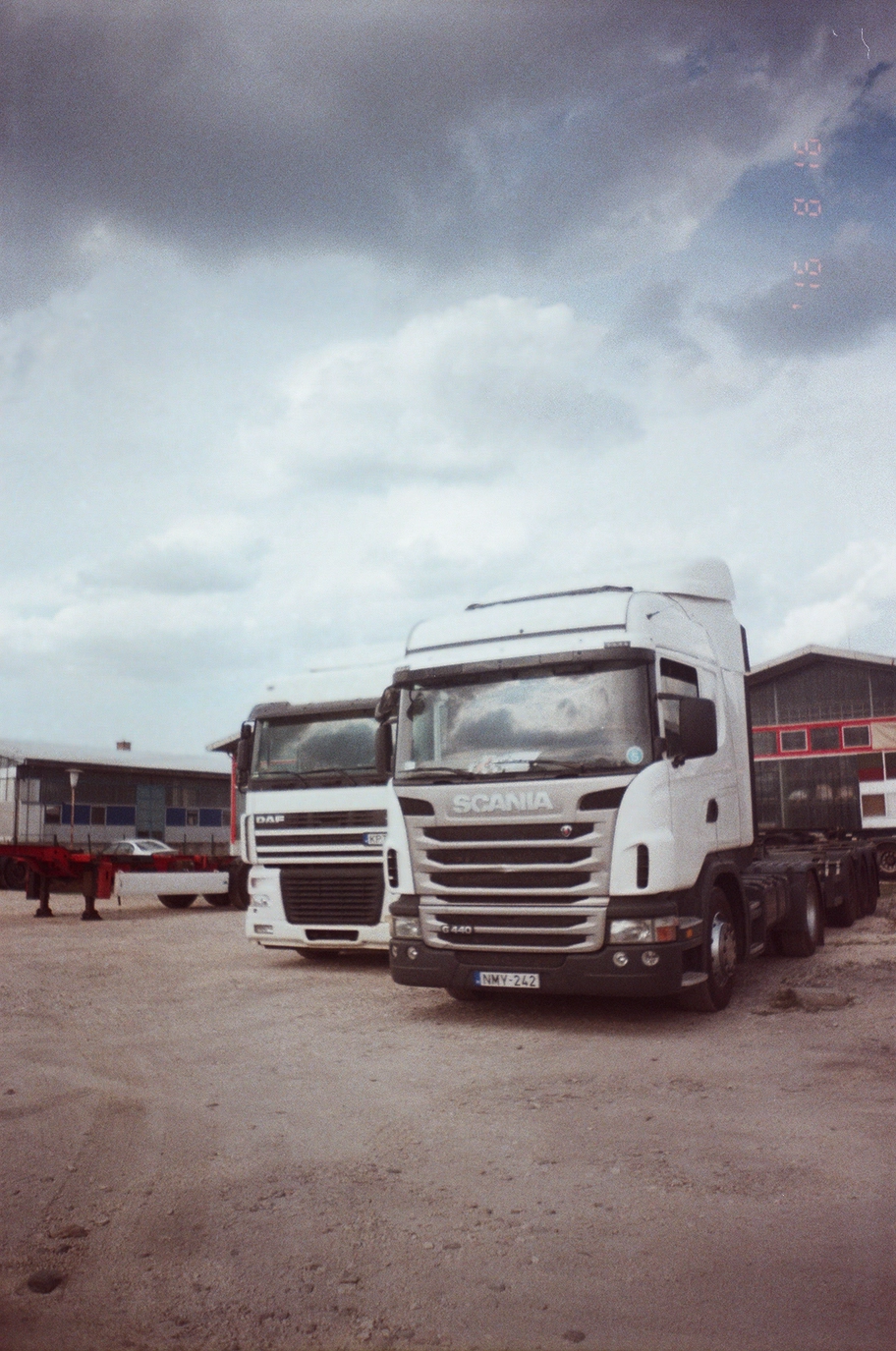 A photo of a white DAF and a white Scania semi truck