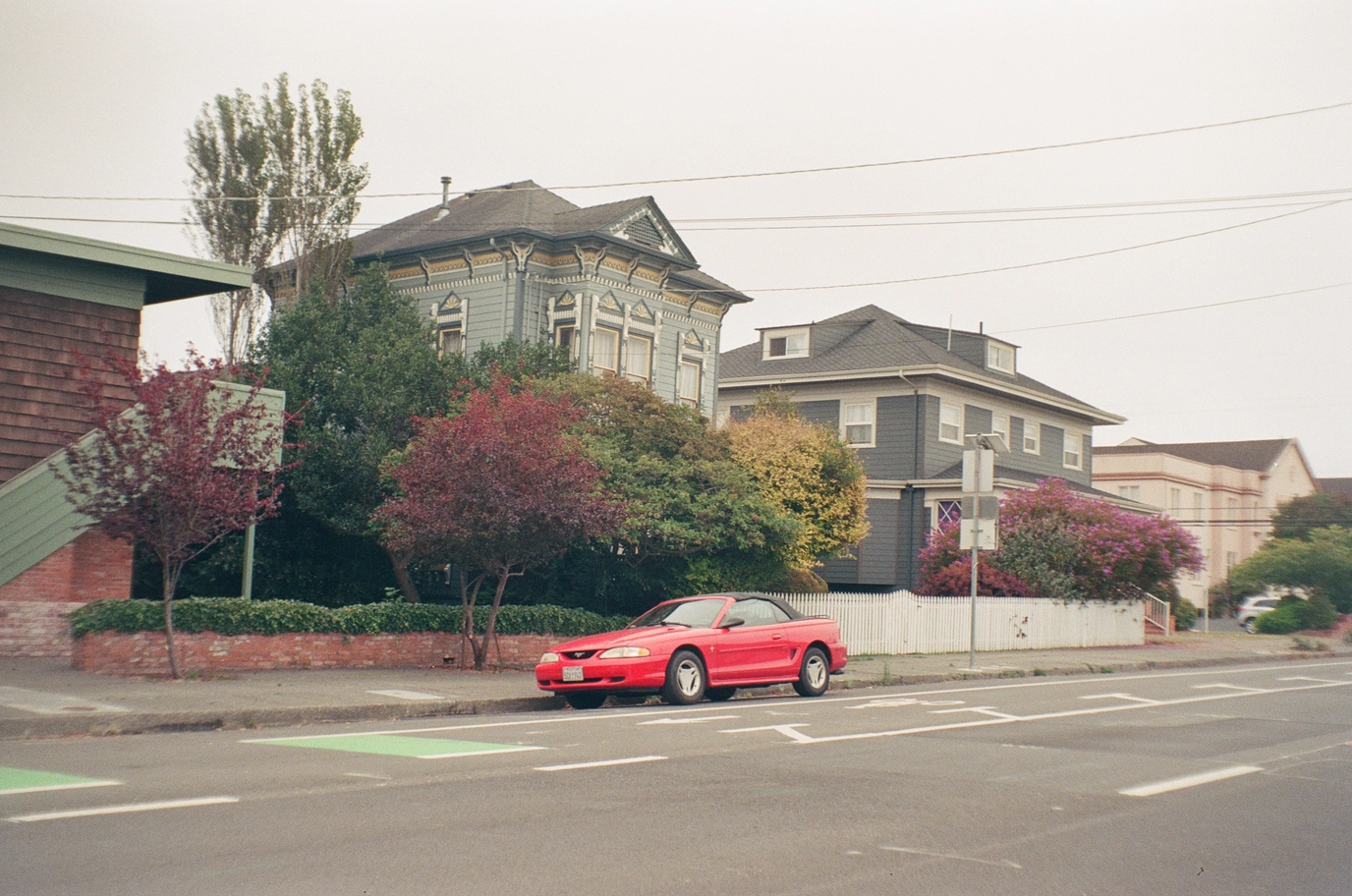A photo of a red 90s mustang on a foggy street