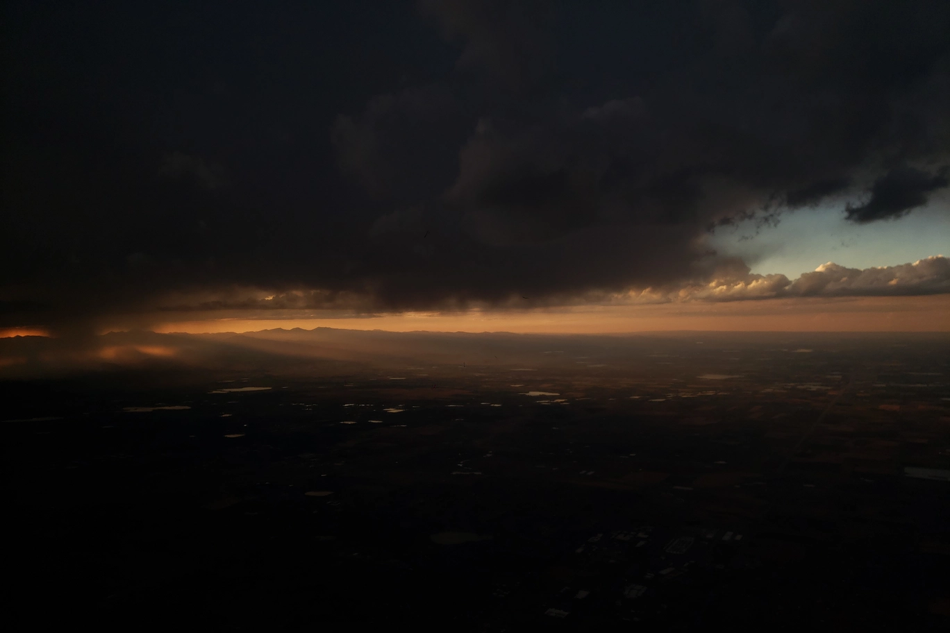 A photo of the sun beaming through the clouds from an airplane