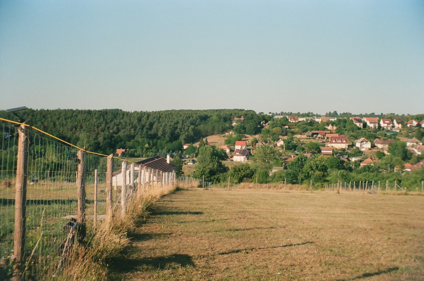 A photo of a fence and a hill with houses