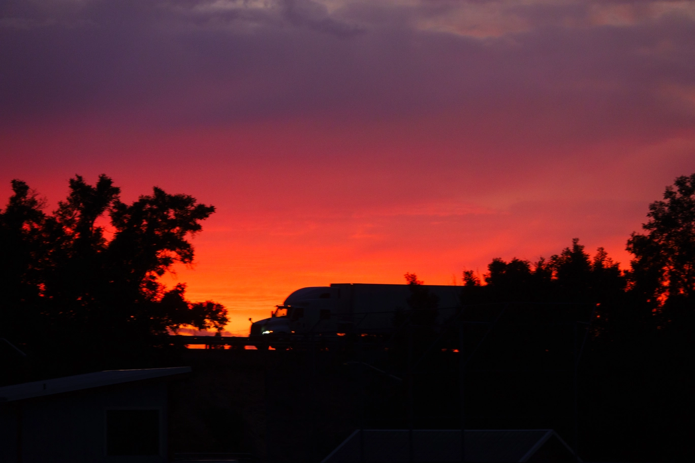 A photo of a semi truck again an orange sky