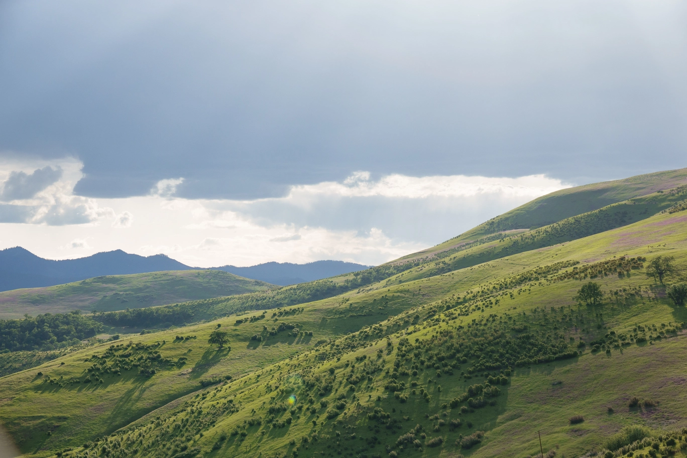 A photo of green hills and clouds