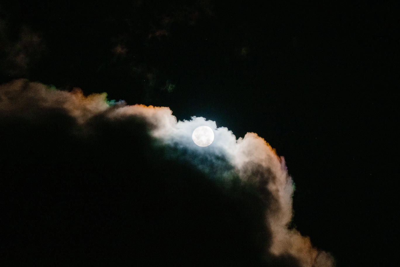 A photo of the moon coming out from behind clouds