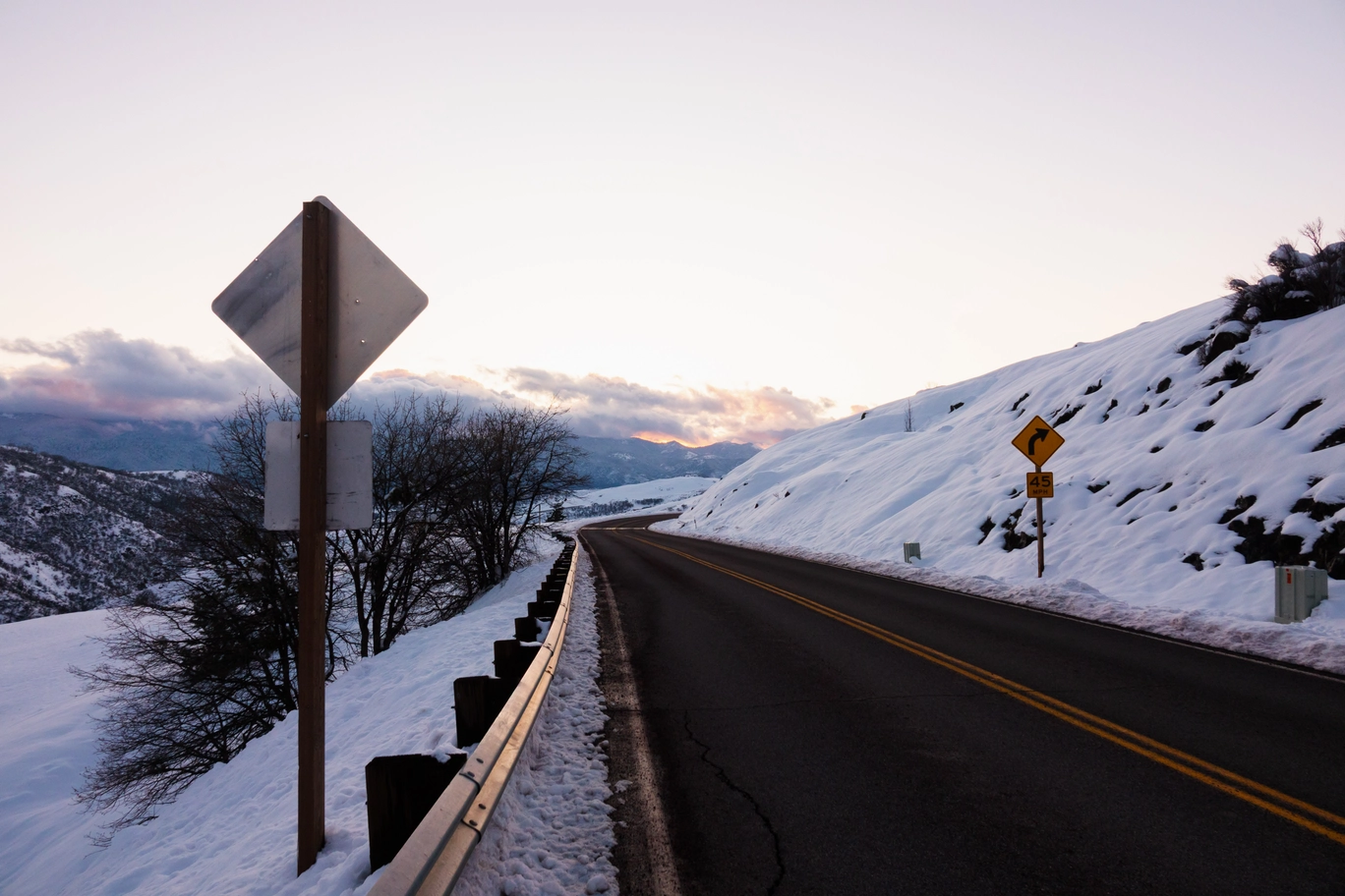 A photo of a snowy mountain road during the sunset