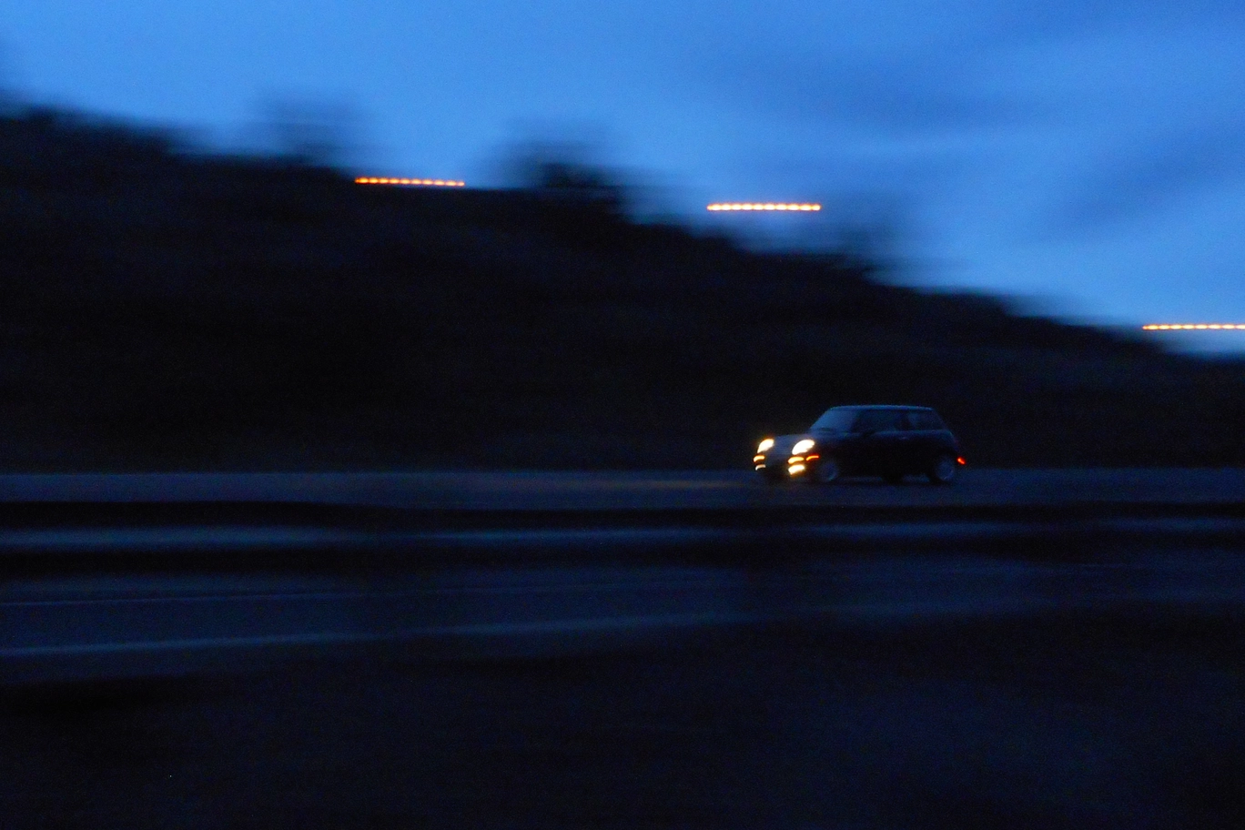 A photo of a black mini cooper on the highway