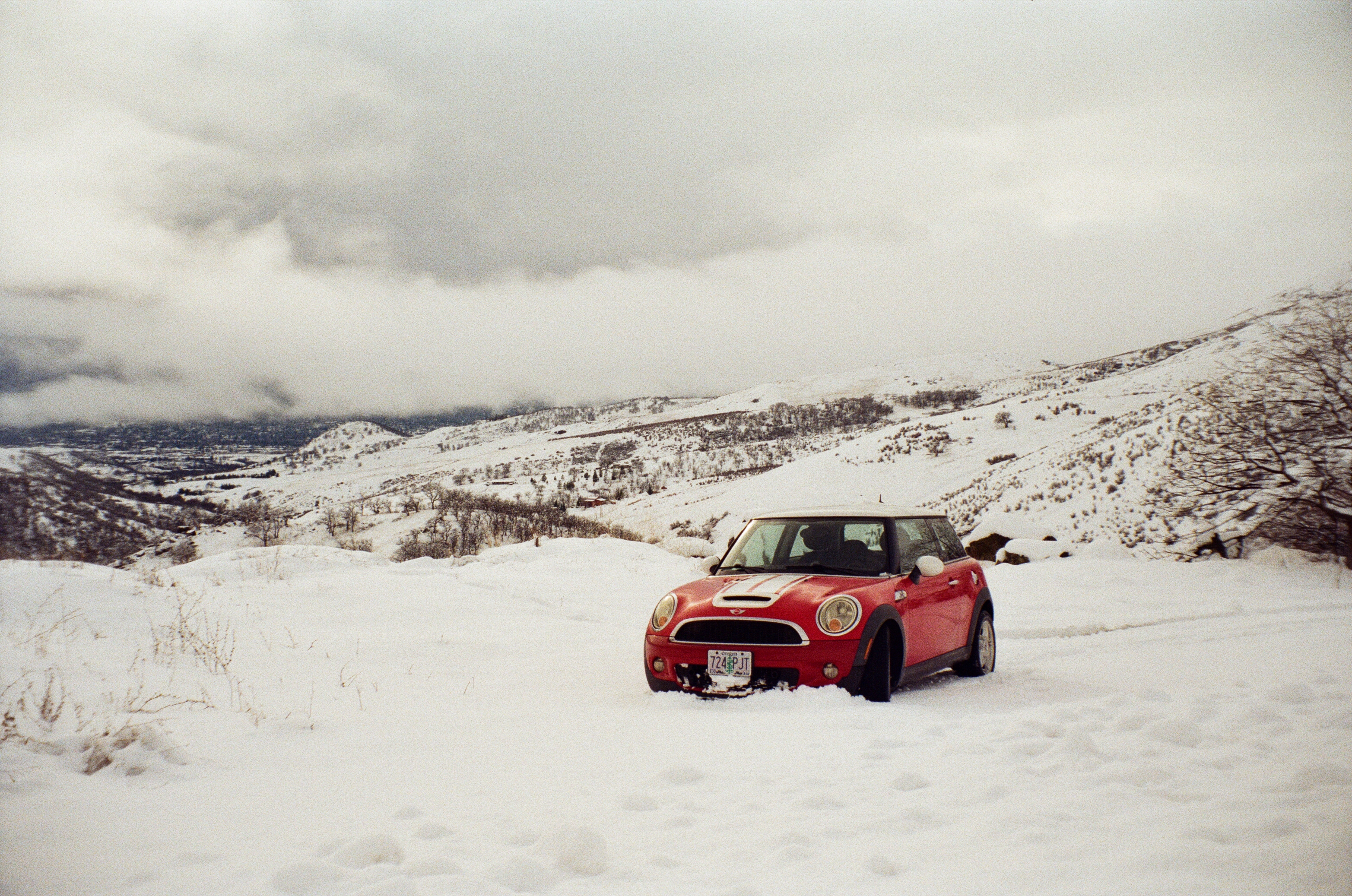 A photo of a red mini cooper in a snowy mountain landscaped