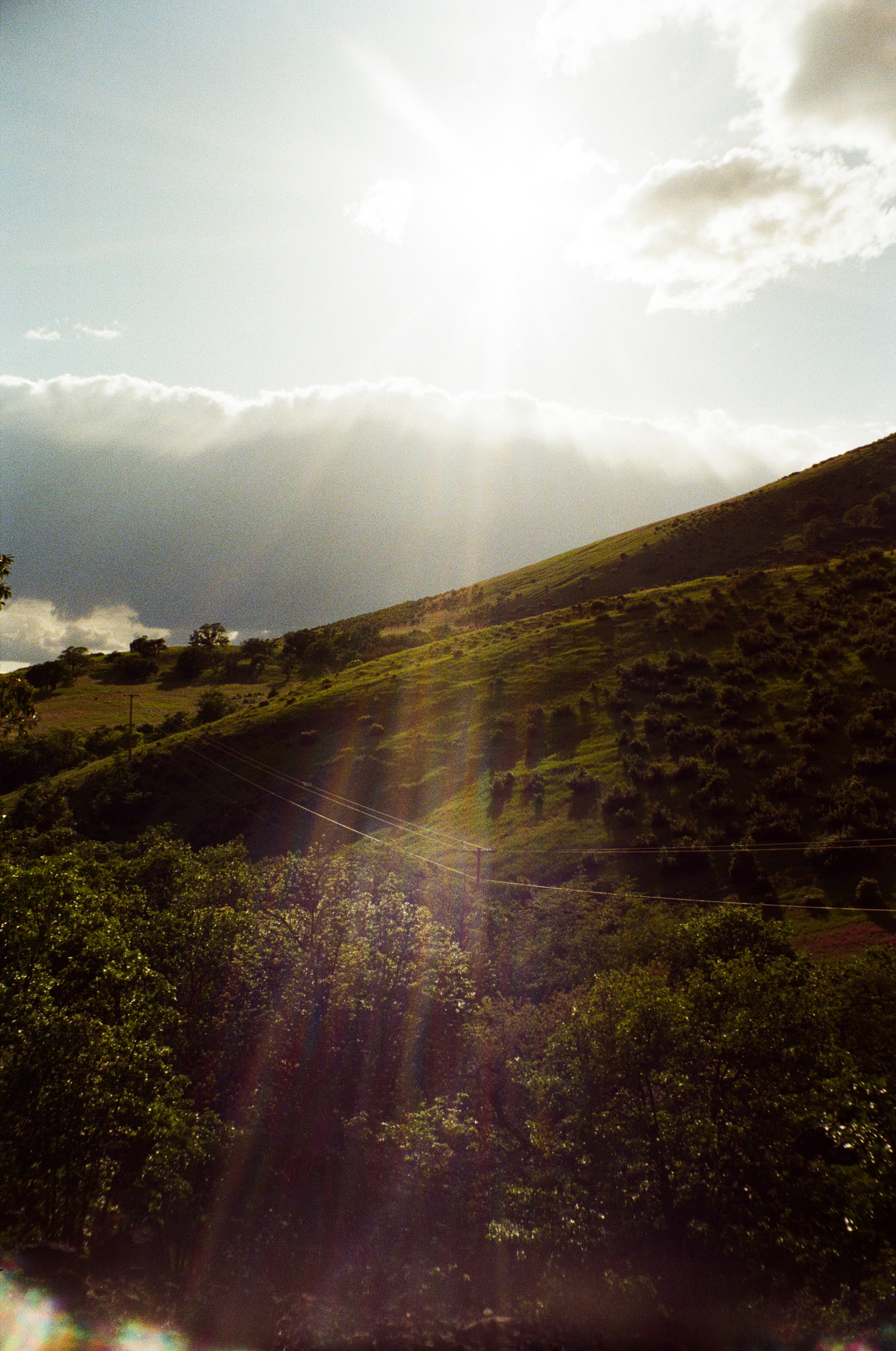 A photo of green hills and the sun