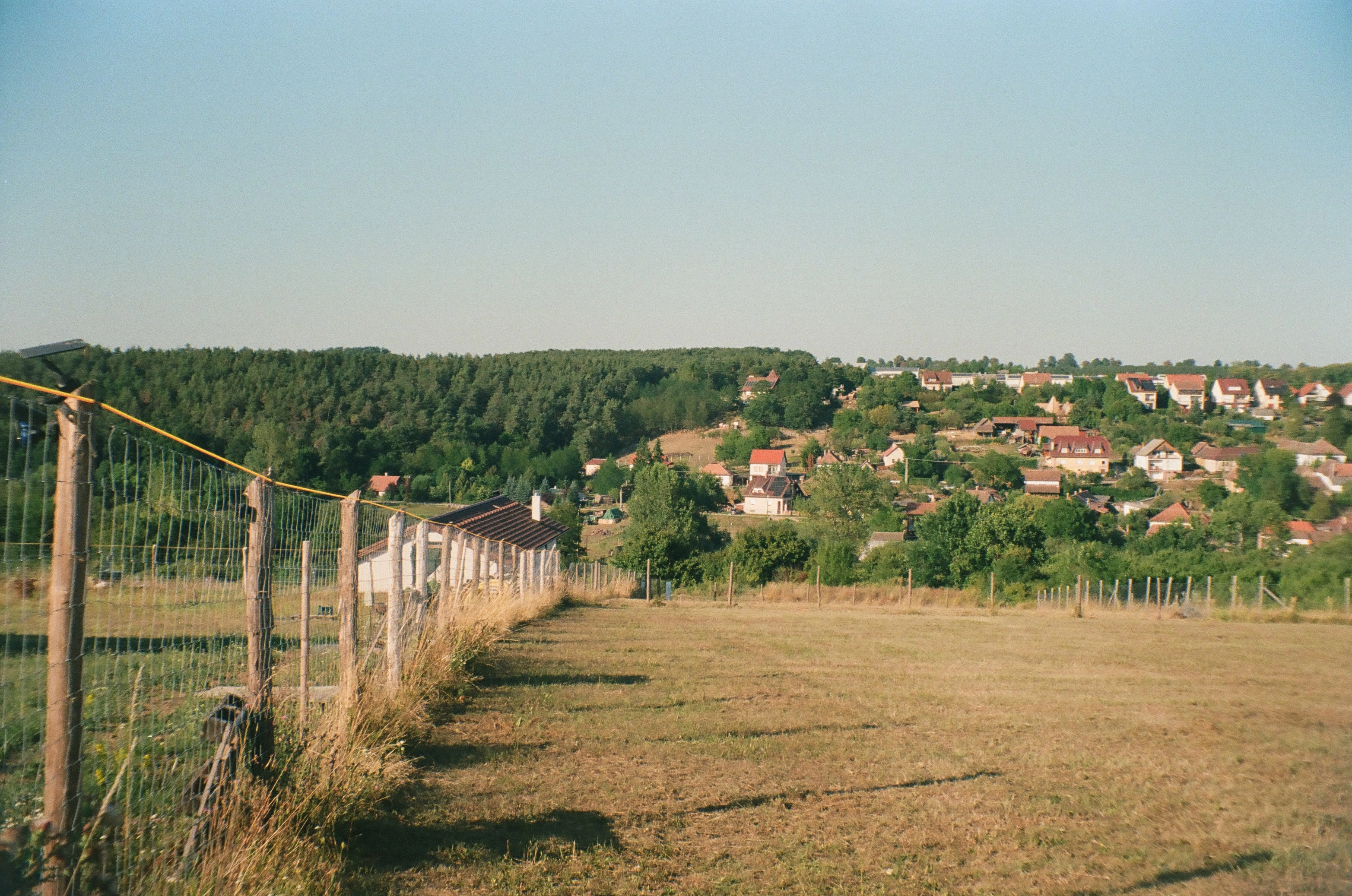 A photo of a fence and a hill with houses