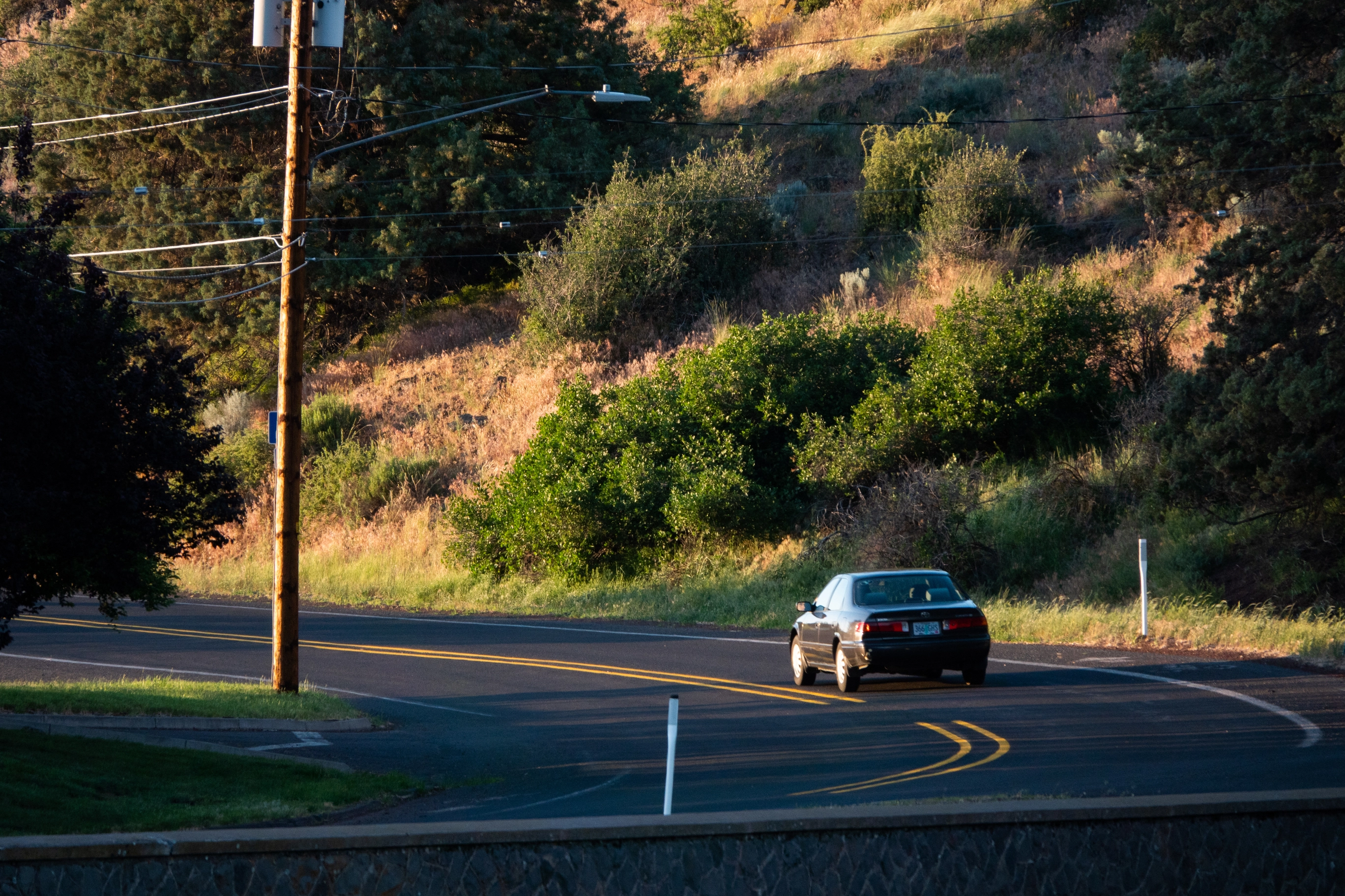 A photo of a car going around the bend during the sunset