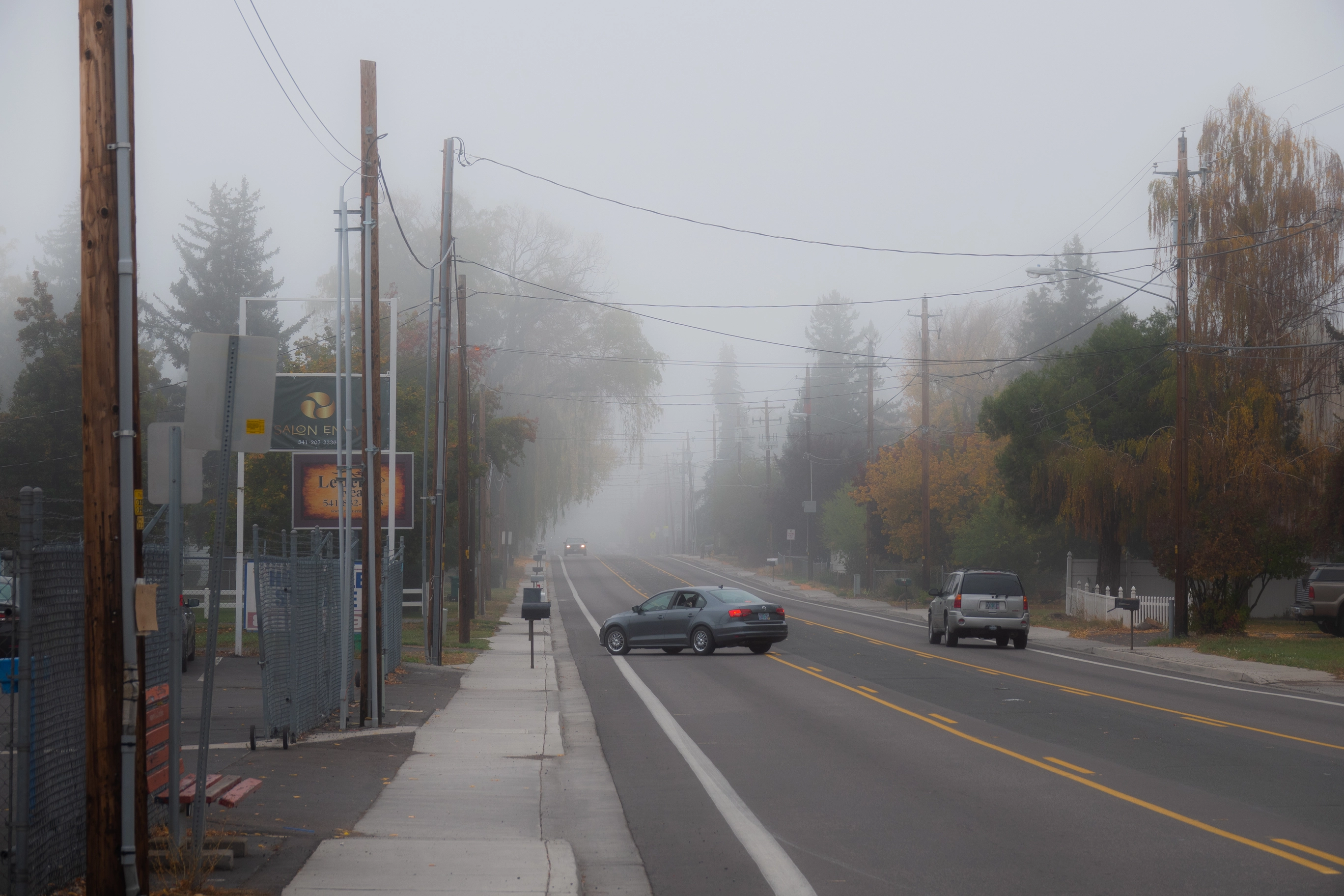 A photo of a car turning off the road on a foggy morning