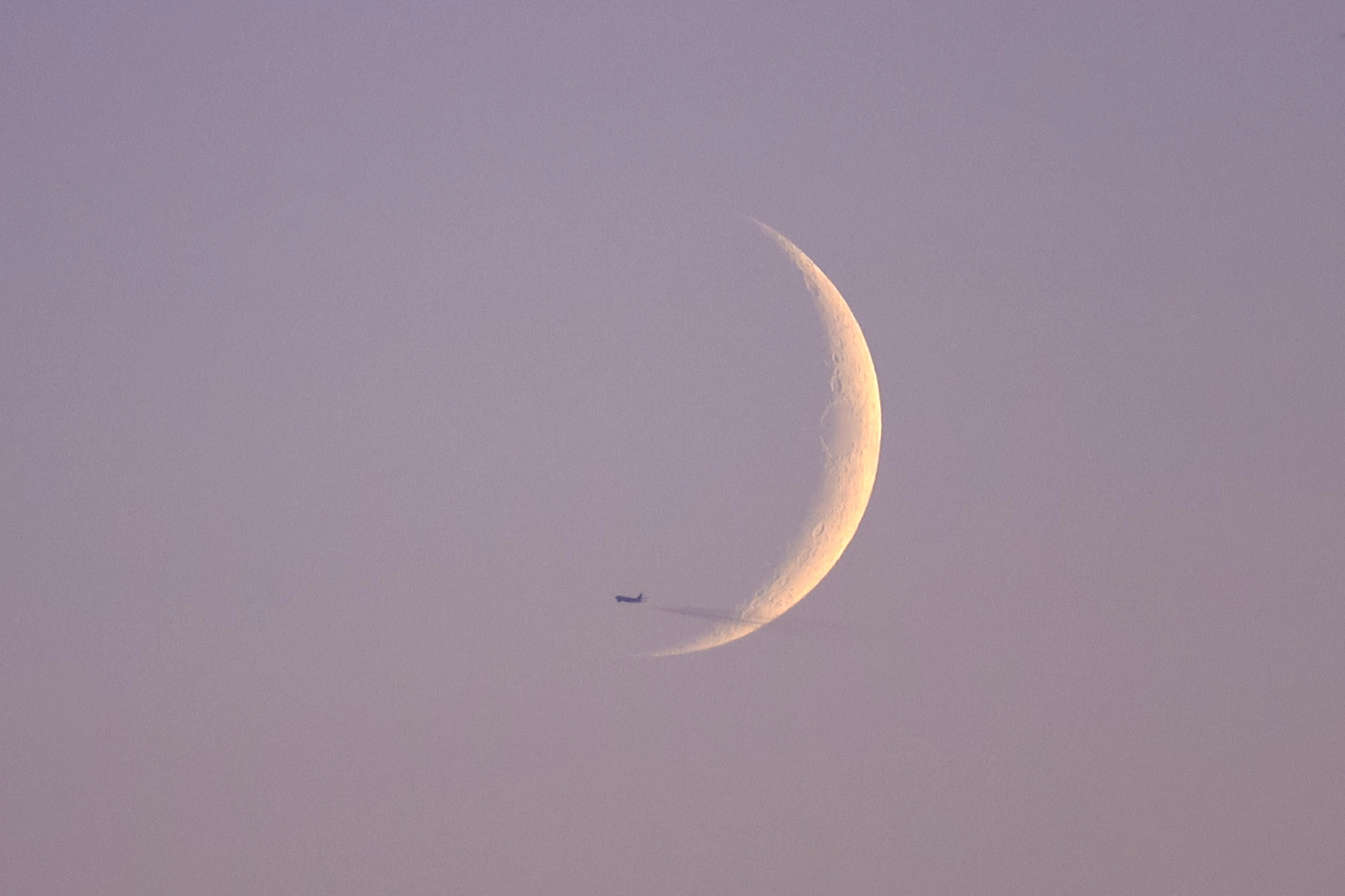 A photo of an airplane flying in front of the moon
